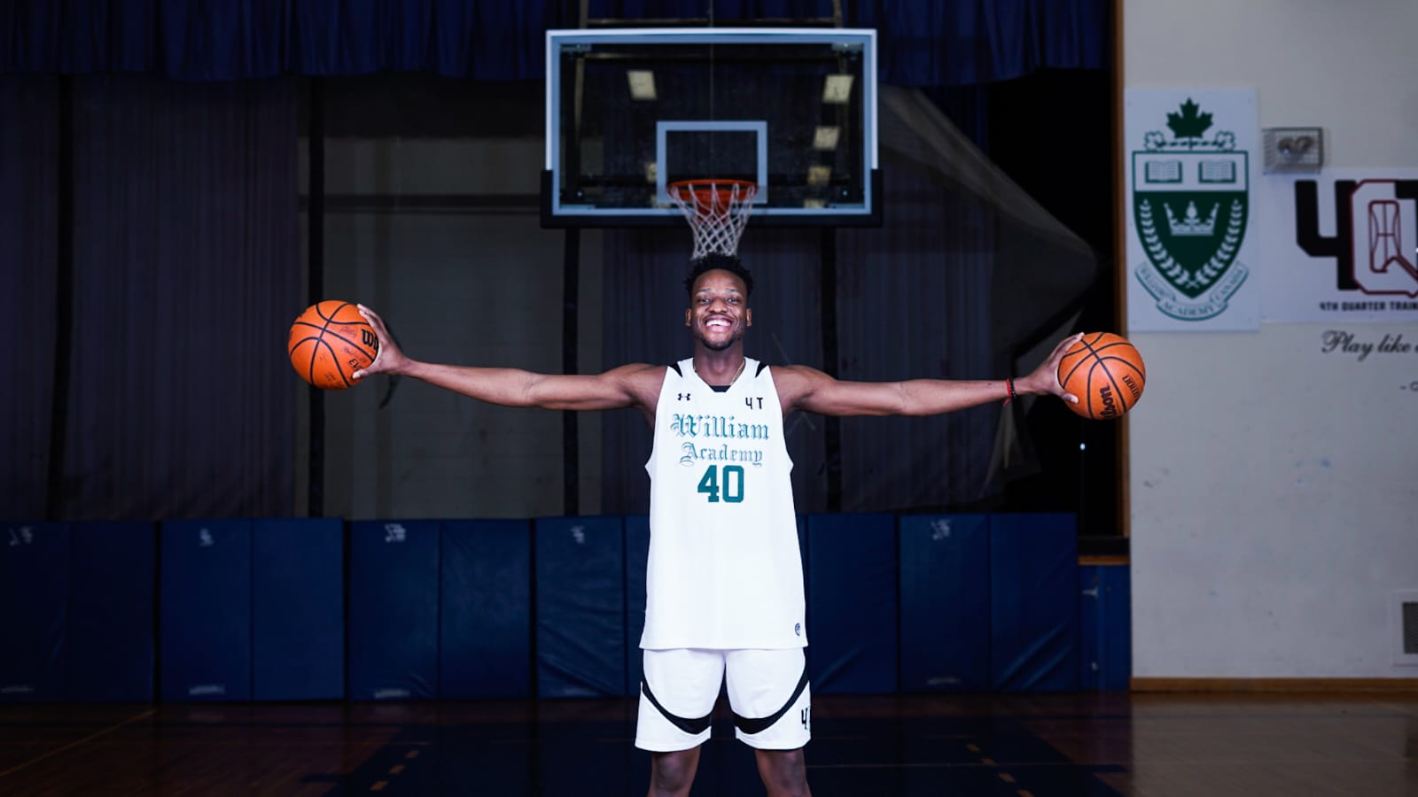 William Academy player with arms spread holding two basketballs
